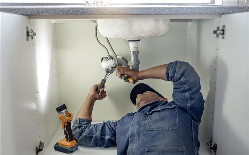 Plumber repairing pipes beneath a bathroom sink in Lomita
